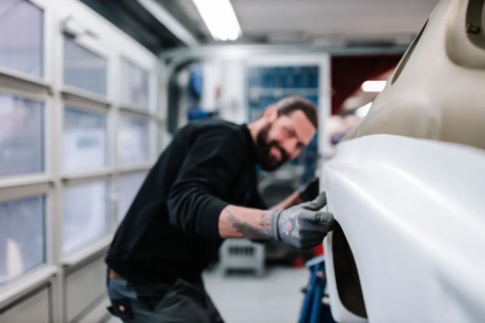 Carrossier bei der Arbeit an einem weissen Auto